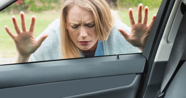 Locked out woman pressed against car window looking at her keys on the seat