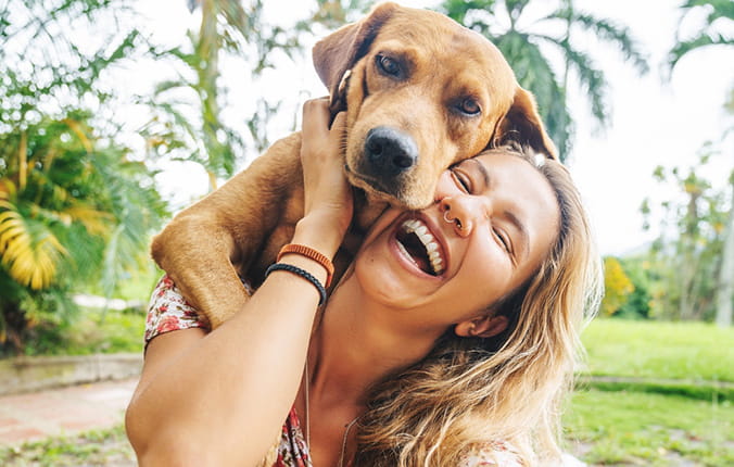 A woman smiling and enjoying a moment with her dog at the park