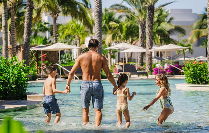Father with kids at the pool at a luxury hotel resort