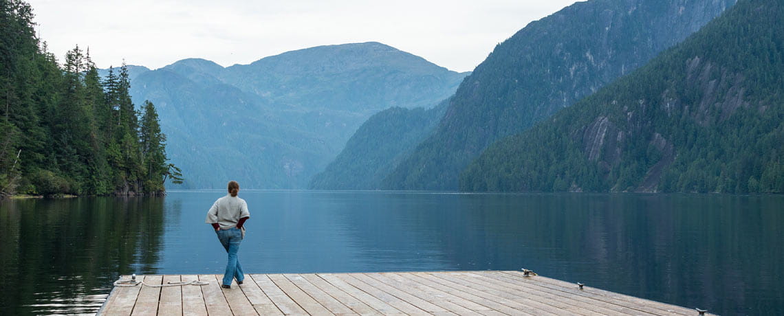 Traveler on dock viewing Alaska mountains