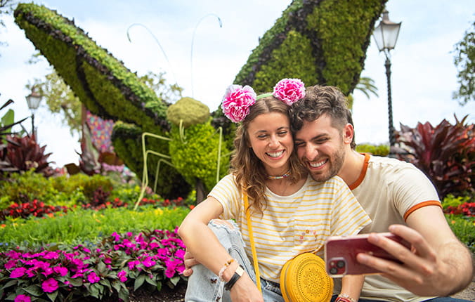 Couple taking selfie in front of floral display in Disney