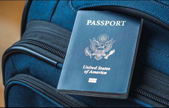 A US Passport tucked into the handle of a blue suitcase