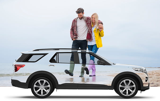 A happy couple takes a walk on the beach, with a transparent overlay of an SUV