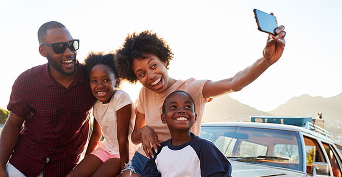 On their family road trip, a happy family pauses for a selfie. 